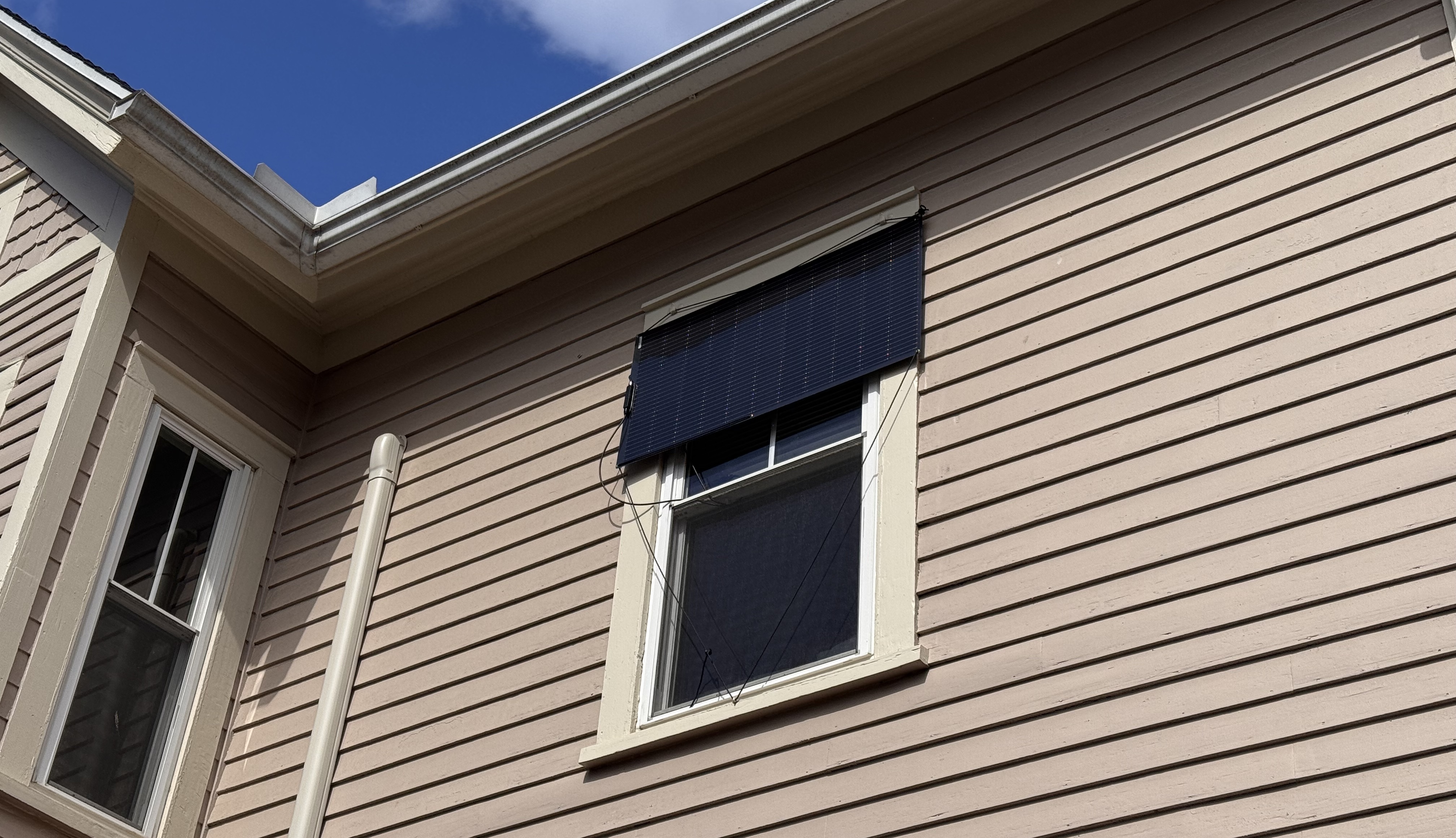 Picture of the solar panel mounted using three mounting points on the exterior casing of a window.